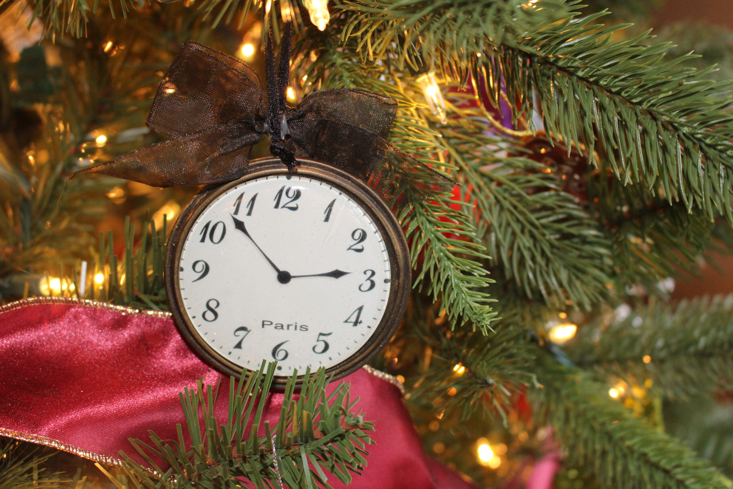 Stopwatch ornament set to 2:55 hanging on a lit Christmas tree