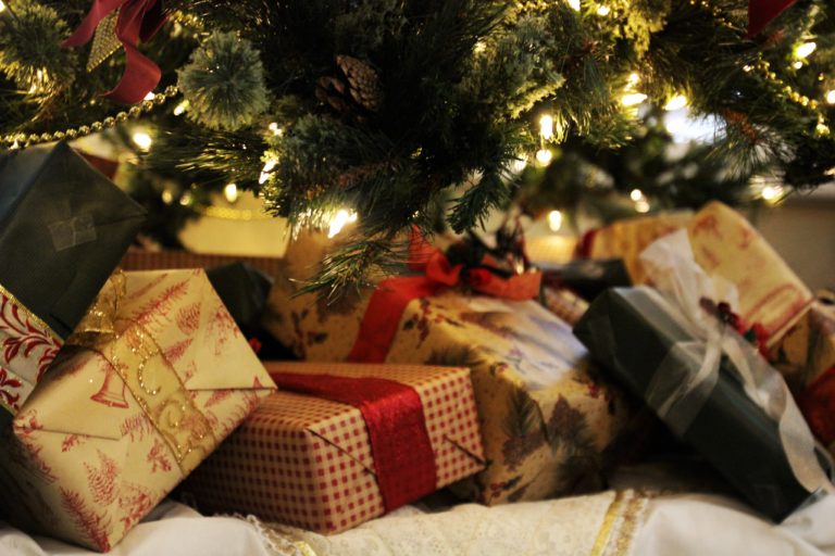 Wrapped Christmas gifts under a lit Christmas tree