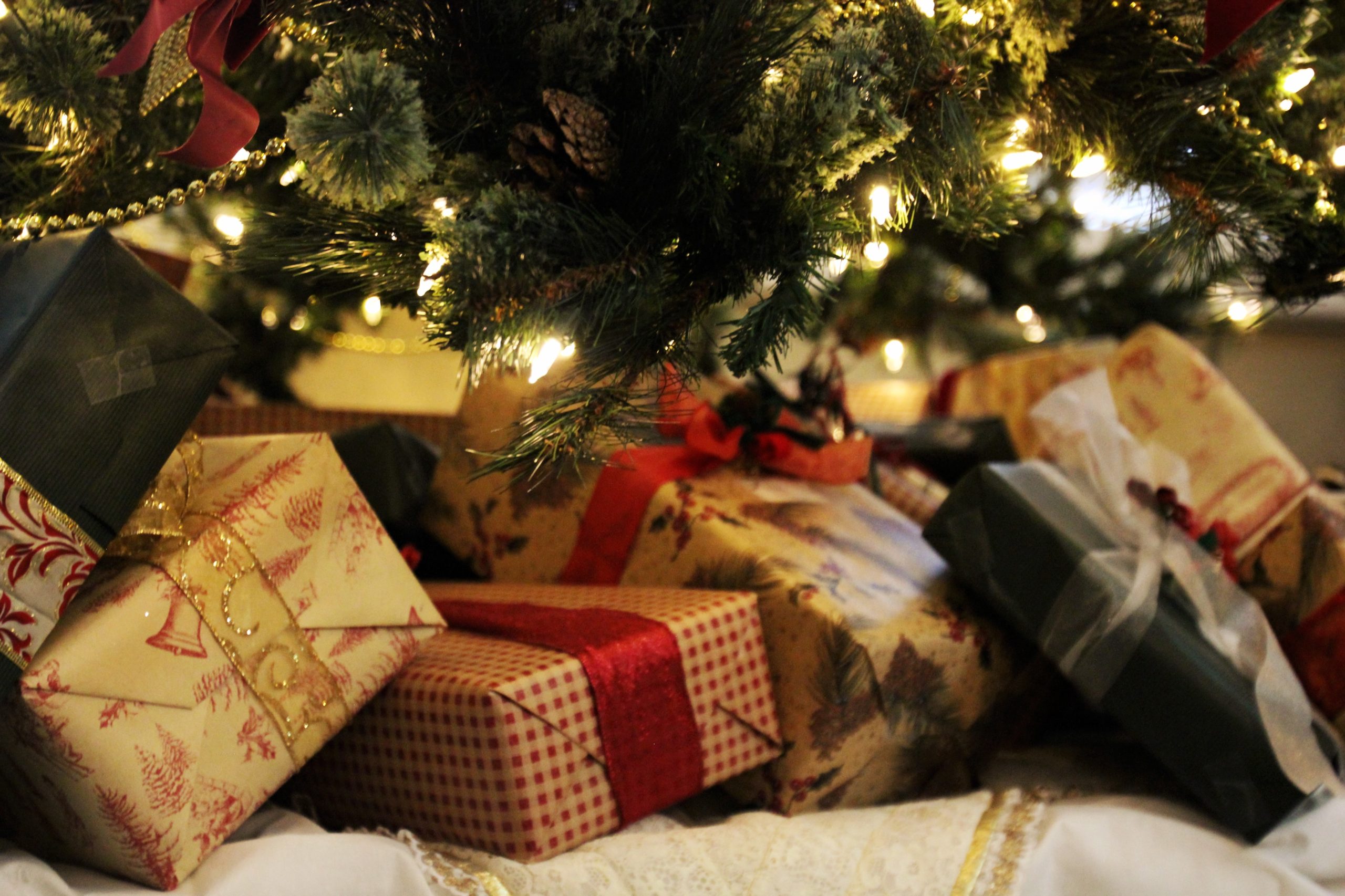 Wrapped Christmas gifts under a lit Christmas tree