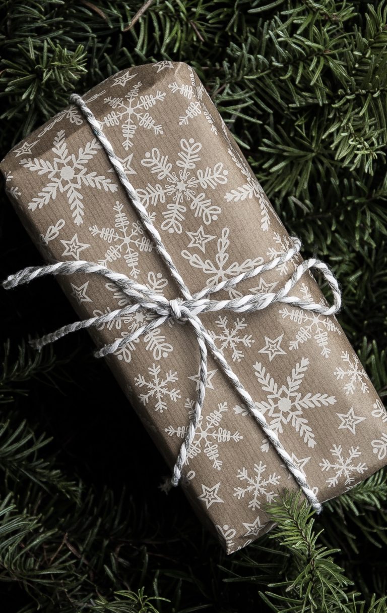 Rectangular gift wrapped in brown paper with white print pattern and tied with white twine