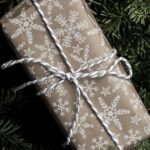 Rectangular gift wrapped in brown paper with white print pattern and tied with white twine