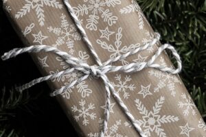 Rectangular gift wrapped in brown paper with white print pattern and tied with white twine
