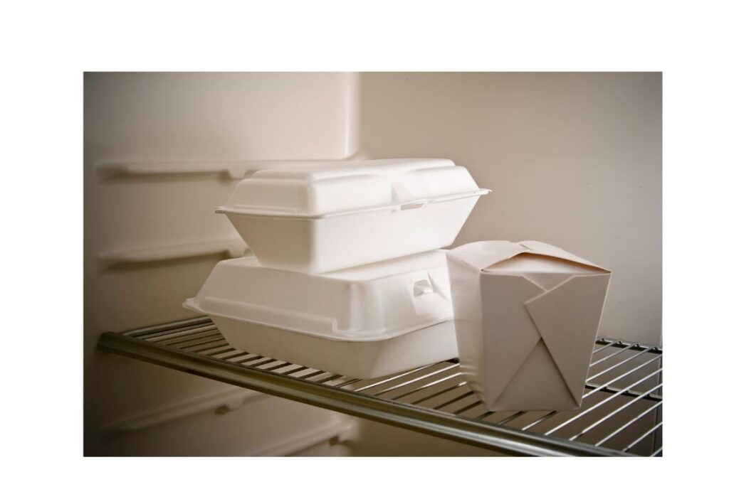 Three take out containers on a refrigerator shelf